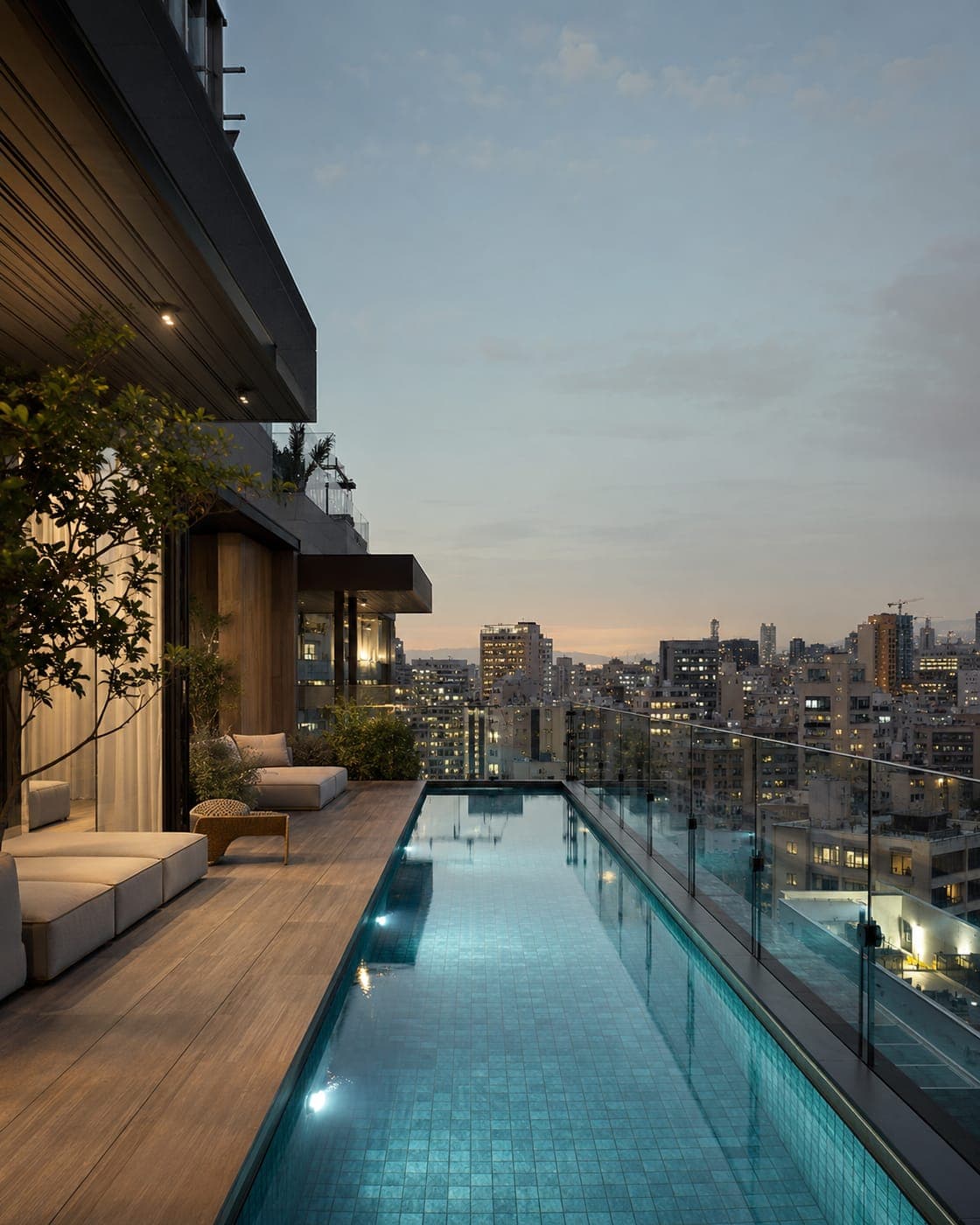 A penthouse terrace with a long pool at dusk