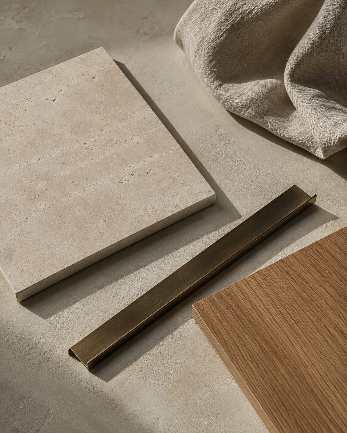 A travertine slab, an oak board, a brass profile and a fold of linen
